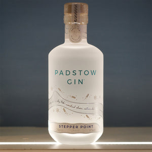 A bottle of Padstow Gin Stepper Point with navy 57% strength, displaying the label and cap against a dark background.