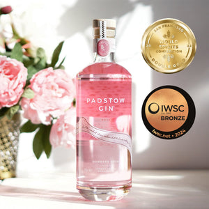 Pink bottle of Padstow Gin with awards on a light background